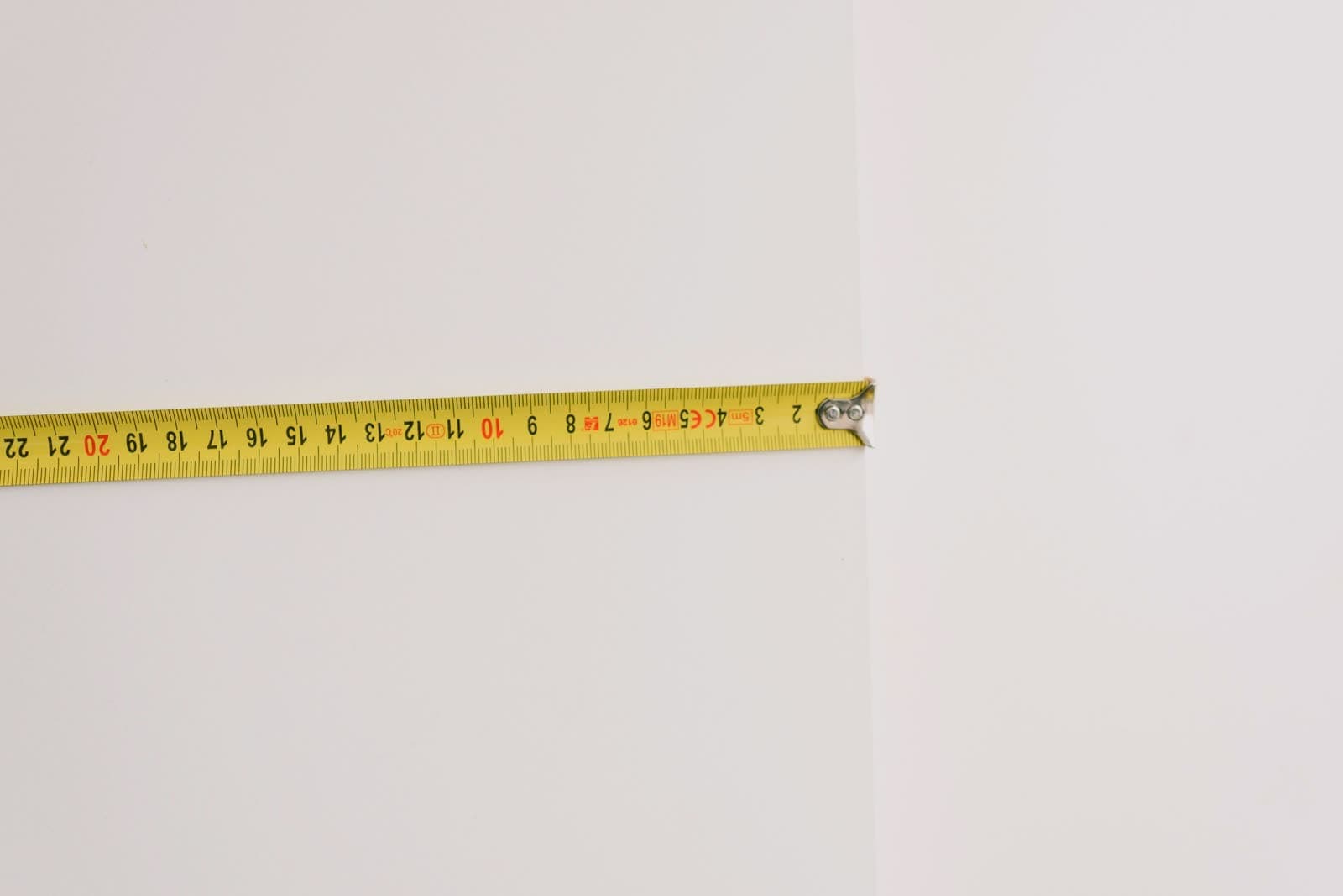 Cinta métrica extendida hasta el canto de un paramento blanco para medir un ancho