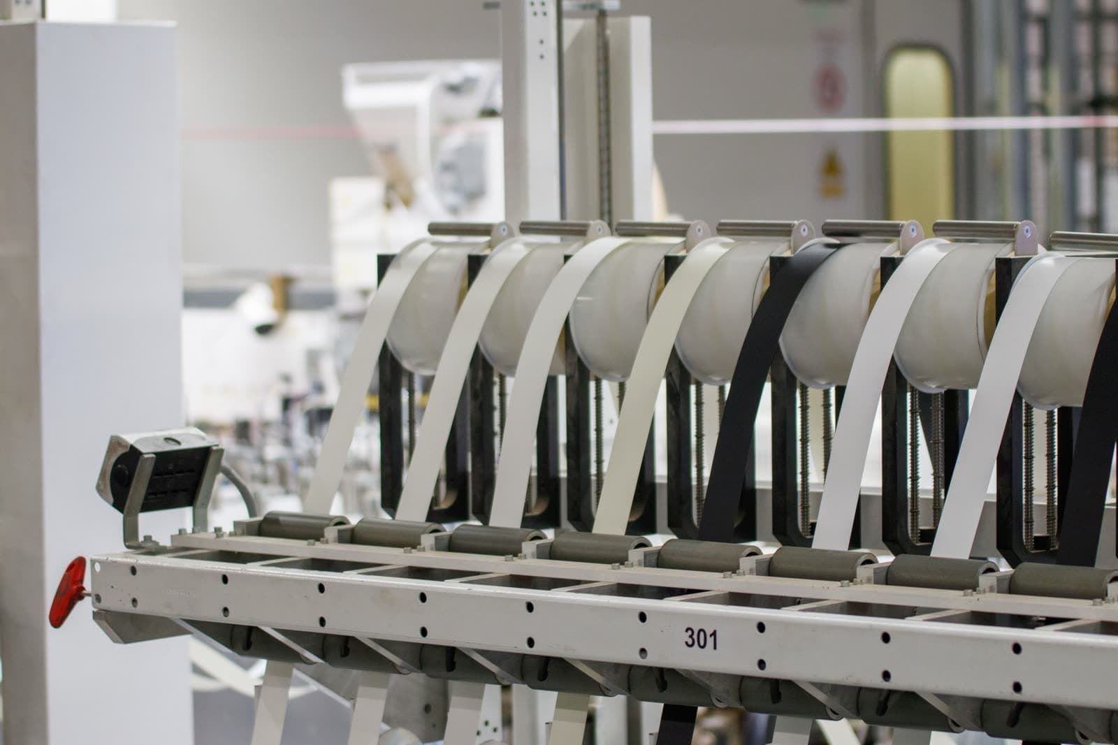 Cintas de tejido claras y oscuras montadas en los rodillos de una máquina
