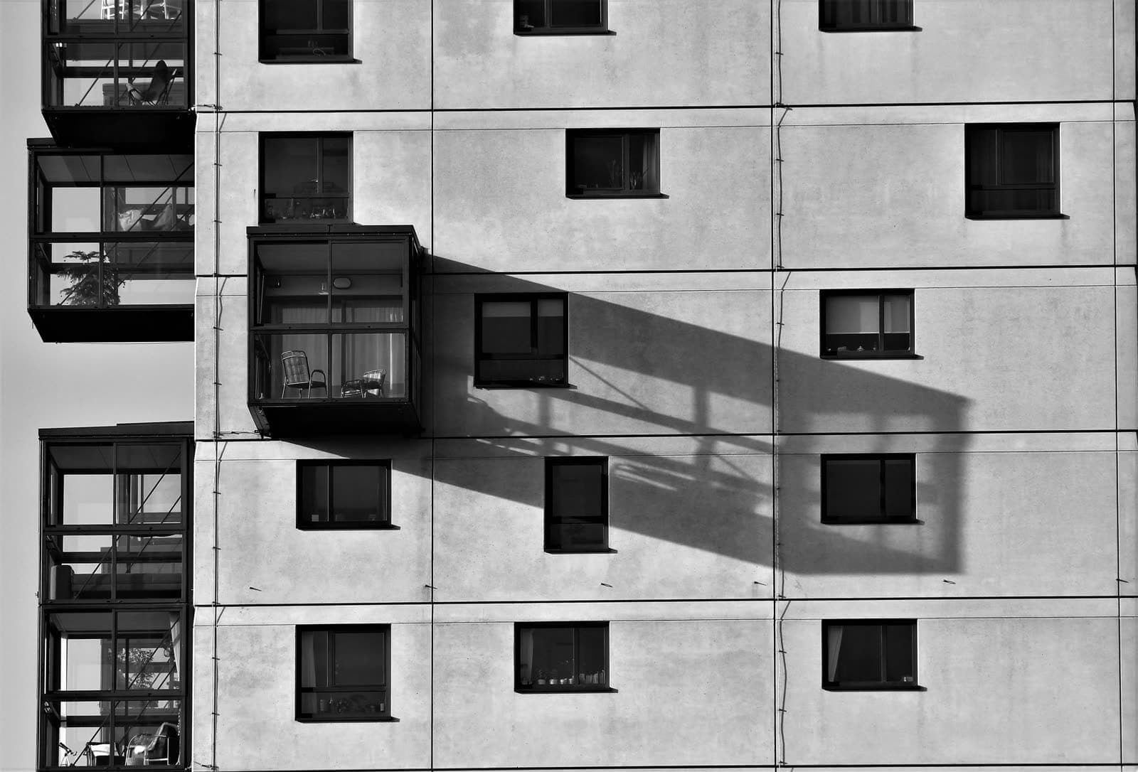 Bloque de viviendas en blanco y negro con galerías acristaladas y ventanas