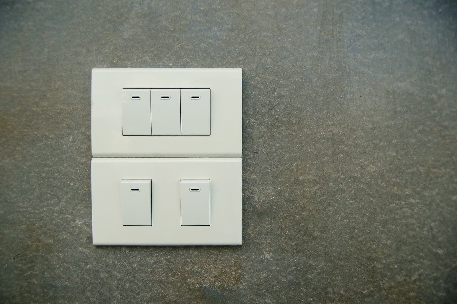Dos placas de interruptores blancos de pared sobre un paramento gris