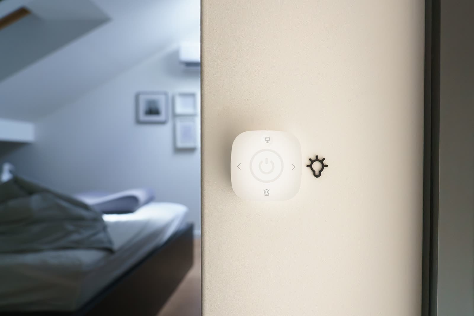 Mando de pared iluminado junto al paso de un dormitorio en penumbra