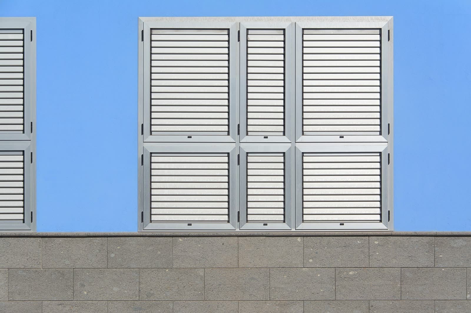 Contraventanas de lamas de aluminio en buen estado sobre una pared azul